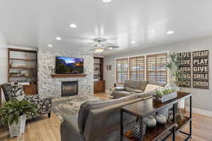 Living room with ceiling fan, light wood-type flooring, and a fireplace