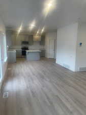 Kitchen with appliances with stainless steel finishes, gray cabinets, and light hardwood / wood-style flooring