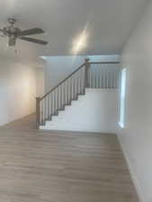 Staircase with hardwood / wood-style flooring and ceiling fan