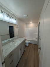 Full bathroom with bathtub / shower combination, hardwood / wood-style floors, vanity, and toilet