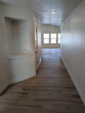 Corridor with a textured ceiling and dark hardwood / wood-style floors