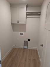 Washroom with light hardwood / wood-style floors and washer hookup