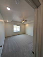 Carpeted spare room featuring ceiling fan and a textured ceiling