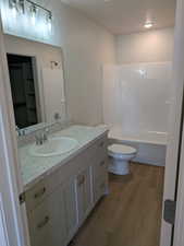 Full bathroom featuring washtub / shower combination, toilet, vanity, and hardwood / wood-style flooring