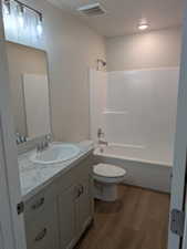 Full bathroom featuring washtub / shower combination, vanity, hardwood / wood-style flooring, and toilet