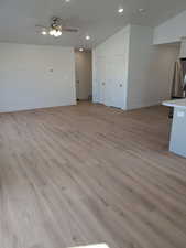 Unfurnished living room featuring light wood-type flooring, vaulted ceiling, and ceiling fan