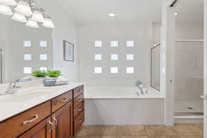 Bathroom with shower with separate bathtub, vanity, and tile patterned floors