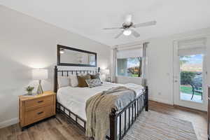 Bedroom with ceiling fan, dark wood-type flooring, access to outside, and multiple windows