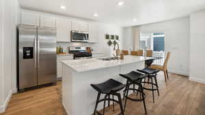 Kitchen with white cabinetry, sink, a center island with sink, and appliances with stainless steel finishes