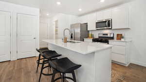 Kitchen featuring a kitchen island with sink, sink, stainless steel appliances, and dark hardwood / wood-style floors