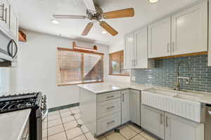 Kitchen featuring kitchen peninsula, appliances with stainless steel finishes, decorative backsplash, sink, and light tile patterned floors