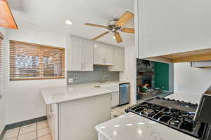 Kitchen with white cabinets, light stone countertops, kitchen peninsula, and appliances with stainless steel finishes