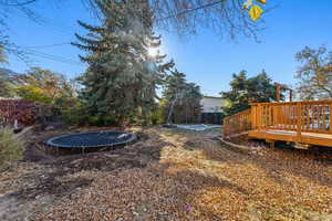 View of yard featuring a deck and a trampoline