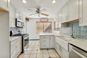 Kitchen featuring ceiling fan, white cabinetry, tasteful backsplash, light tile patterned floors, and appliances with stainless steel finishes