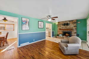 Living room featuring a fireplace, light wood-type flooring, and ceiling fan