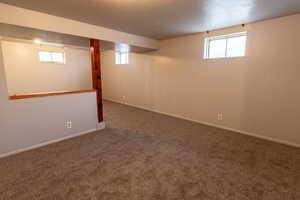 Basement featuring carpet, a healthy amount of sunlight, and a textured ceiling