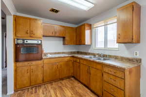 Kitchen featuring white stovetop, light hardwood / wood-style flooring, black oven, and sink