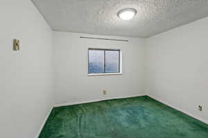 Carpeted empty room with a textured ceiling