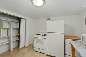 Kitchen with light tile patterned floors and white appliances