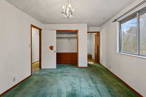 Unfurnished bedroom featuring a closet, carpet floors, a chandelier, and a textured ceiling