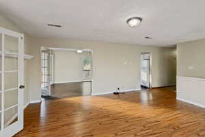 Unfurnished room with french doors, hardwood / wood-style floors, and a textured ceiling