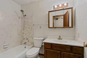 Full bathroom with vanity, toilet, washtub / shower combination, and a textured ceiling