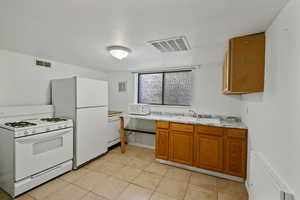 Kitchen with sink, light tile patterned flooring, and white appliances