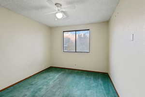 Carpeted spare room featuring a textured ceiling and ceiling fan