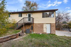 Back of house with a lawn and central air condition unit