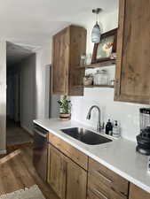 Kitchen with pendant lighting, dishwasher, dark wood-type flooring, sink, and tasteful backsplash