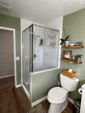 Bathroom with hardwood / wood-style flooring, toilet, and walk in shower