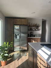 Kitchen with stainless steel fridge, light stone countertops, and dark hardwood / wood-style floors