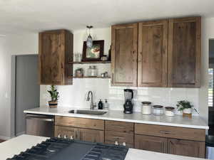 Kitchen with stainless steel dishwasher, backsplash, pendant lighting, and sink