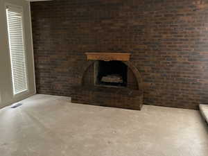 Interior space with a fireplace, dark carpet, and brick wall