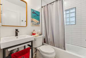 Full bathroom with sink, shower / bath combo, and toilet