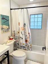 Bathroom featuring toilet, tile patterned floors, and shower / bathtub combination with curtain