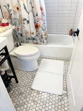 Bathroom featuring tile patterned floors, toilet, and shower / bathtub combination with curtain