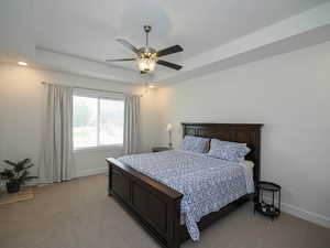 Master bedroom featuring a raised ceiling and ceiling fan