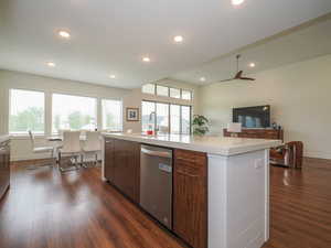 Kitchen with dishwasher, a kitchen island with sink, sink, ceiling fan, and dark hardwood / wood-style flooring