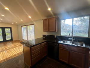 Kitchen featuring kitchen peninsula, sink, dishwasher, dark hardwood / wood-style floors, and lofted ceiling