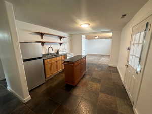 Kitchen featuring stainless steel fridge, white electric range, a kitchen island, and sink