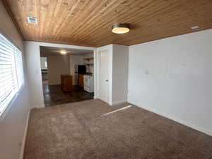 Carpeted empty room featuring wooden ceiling