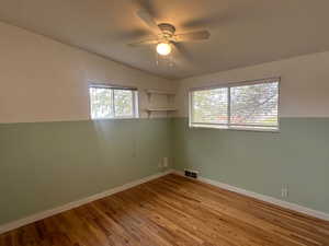 Spare room with plenty of natural light, ceiling fan, light wood-type flooring, and vaulted ceiling