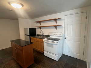 Kitchen featuring electric stove, stainless steel fridge, sink, and a kitchen island