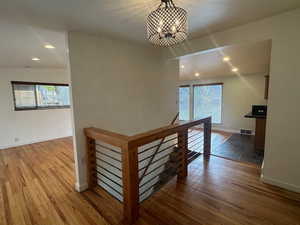 Hall featuring vaulted ceiling, plenty of natural light, dark wood-type flooring, and a notable chandelier