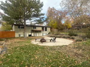 Rear view of property featuring a yard and a fire pit