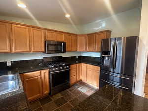 Kitchen featuring appliances with stainless steel finishes, lofted ceiling, and sink