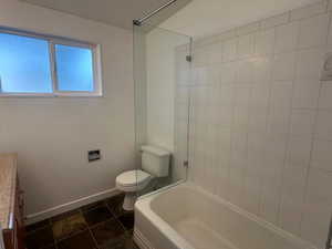 Full bathroom with tile patterned floors, vanity, toilet, and tiled shower / bath combo