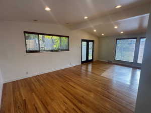 Spare room with hardwood / wood-style floors, vaulted ceiling with beams, and french doors