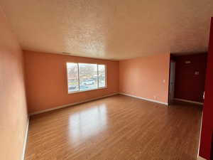 Unfurnished room featuring wood-type flooring and a textured ceiling